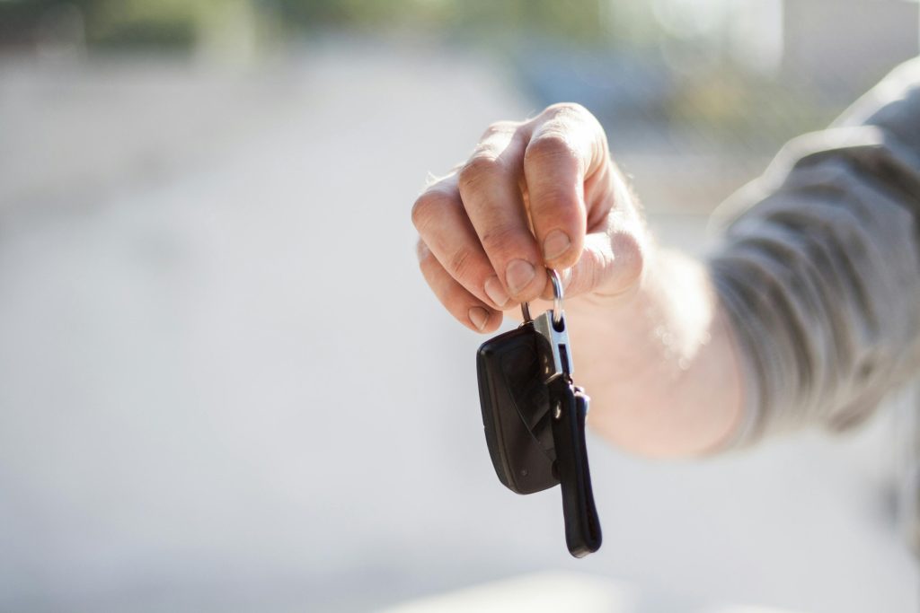 pexels-photo-97079-97079 Close-up of a hand handing over car keys, signifying purchase or rental.