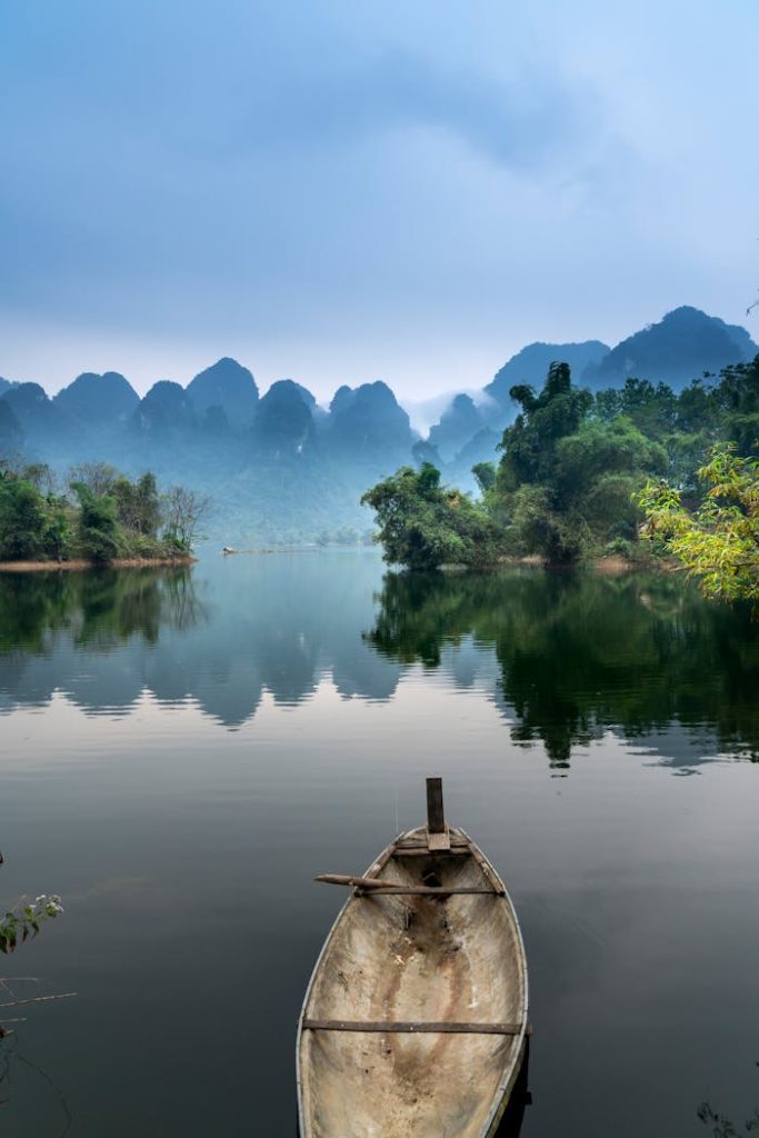 photo-of-a-boat-on-a-river-2178175 A tranquil river scene with a canoe, misty mountains, and lush greenery, perfect for nature lovers.