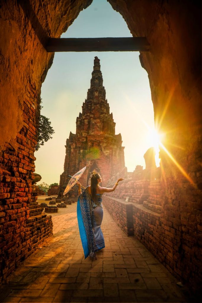 woman-wearing-blue-dress-with-umbrella-during-sunset-2070485 A woman in traditional wear stands with an umbrella at a historic Ayutthaya temple during sunset.